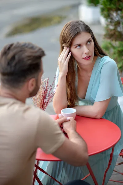 Sad couple sitting in open air cafe, having argument