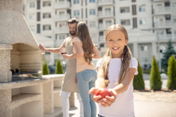 Menina bonita mostrando tomates e sorrindo bem — Fotografia de Stock