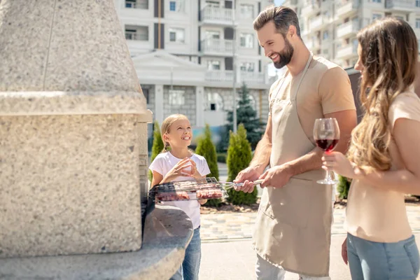 Buena familia teniendo barbacoa y luciendo feliz — Foto de Stock