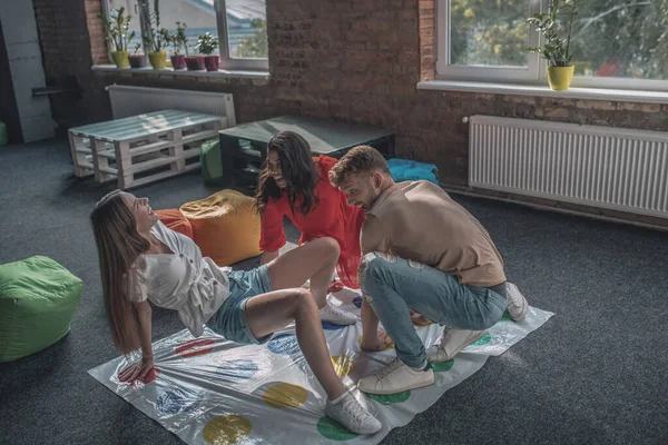 Τρεις φίλοι παίζουν twister στο πάτωμα — Φωτογραφία Αρχείου