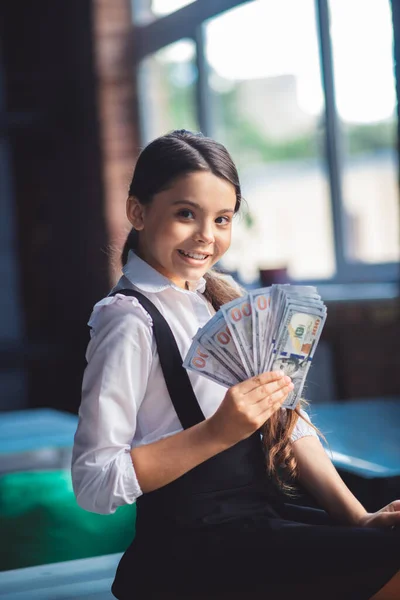 Flicka i vit skjorta håller dollar och ser glad ut — Stockfoto
