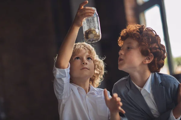 Due ragazzi che guardano il barattolo con le monete — Foto Stock