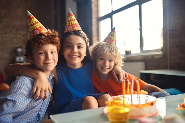 Három gyerek ünnepli a napot, és boldognak tűnnek. — Stock Fotó