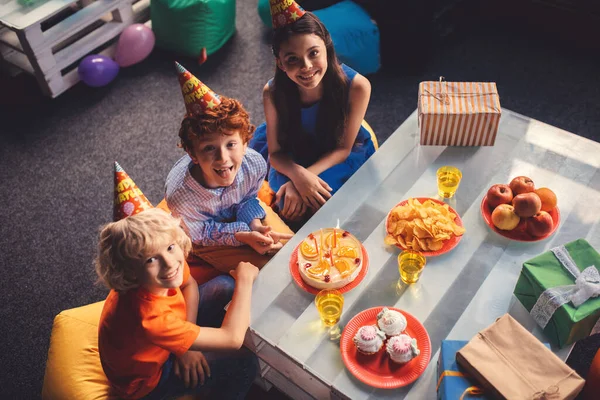 Tre bambini seduti a tavola con cibo dolce — Foto Stock