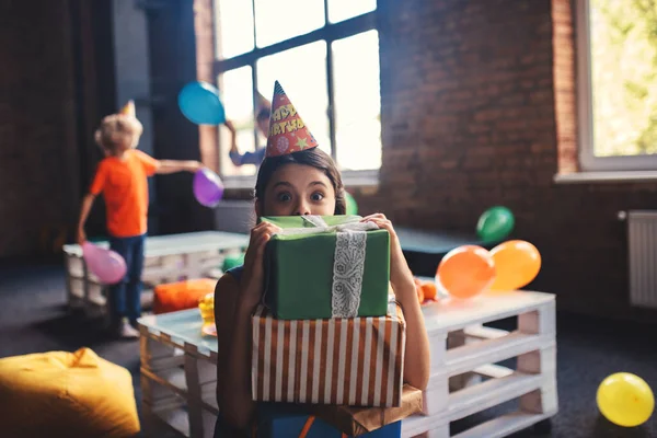 Cute girl w kapeluszu gospodarstwa prezenty i uczucie zdumiony — Zdjęcie stockowe