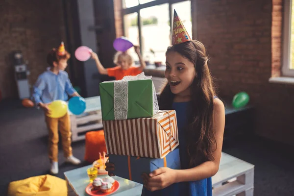 Schattig meisje in een hoed met cadeautjes en kijken opgewonden — Stockfoto