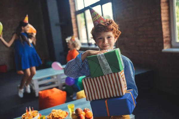 Leuke roodharige jongen met cadeautjes en een glimlach — Stockfoto