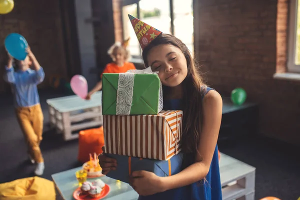 Schattig meisje in een hoed met cadeautjes en glimlach — Stockfoto