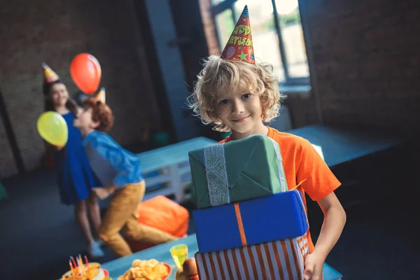 Lieve blonde jongen met cadeautjes en glimlach — Stockfoto