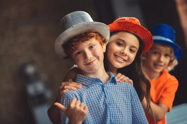 Tres niños en sombreros de fiesta sintiéndose bien y sonriendo —  Fotos de Stock