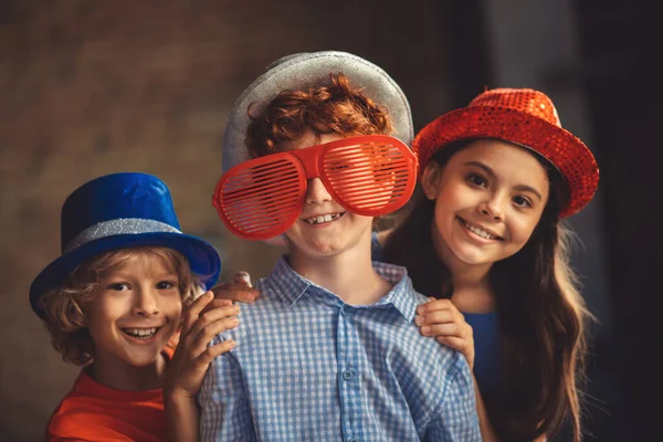 Tre bambini in cappelli da festa si sentono felici e divertiti — Foto Stock
