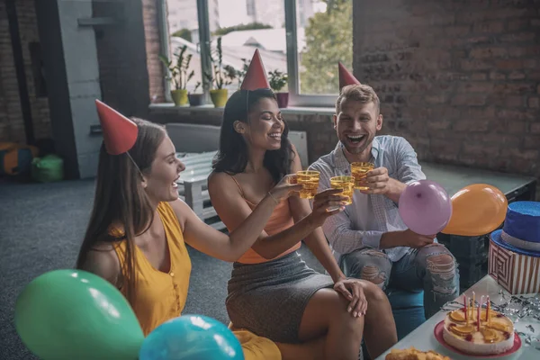 Vreugdevolle jonge vrienden drinken alcohol tijdens het verjaardagsfeest — Stockfoto