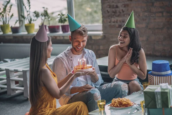 Amigos presentando un pastel de cumpleaños a un hombre de cumpleaños —  Fotos de Stock