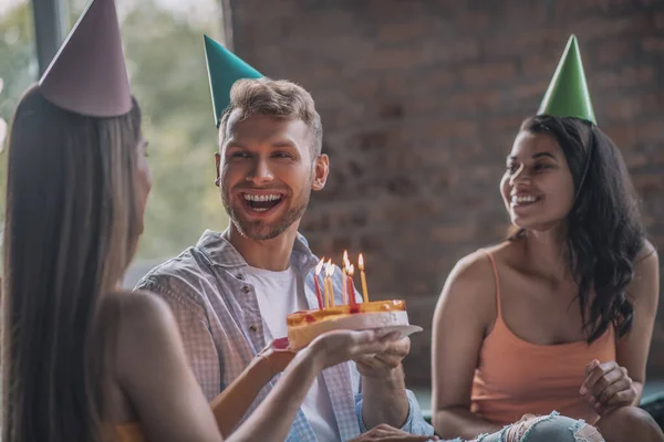 생일 케이크에 촛불을 밝히는 미소짓는 사람 — 스톡 사진