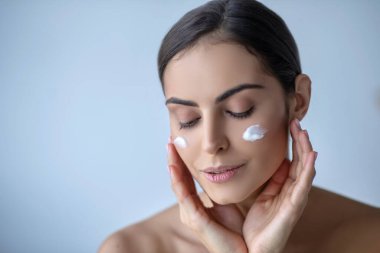 Yanaklarında krema olan tatlı bir kadın. Rahatlamış görünüyor.