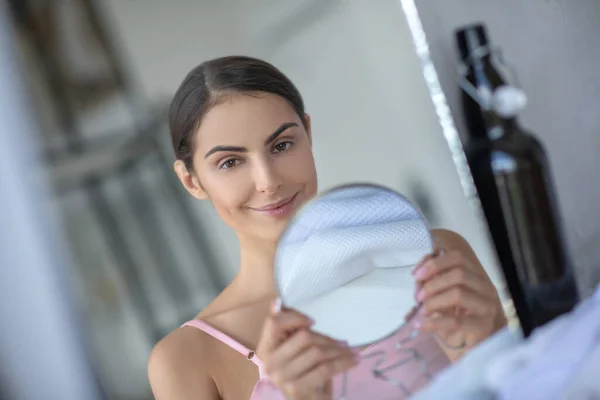 Leuke vrouw in roze lingerie houden van een ronde spiegel — Stockfoto