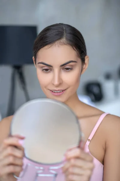 Mujer bonita en lencería rosa sosteniendo un espejo redondo — Foto de Stock
