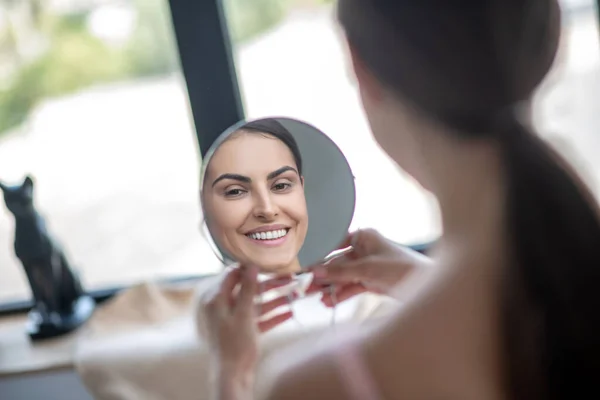 Leuke vrouw in roze lingerie kijken in de spiegel en glimlachen — Stockfoto