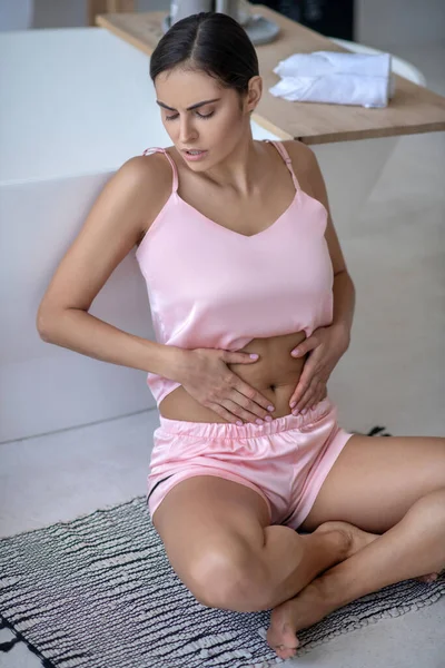 Mujer de color rosa con dolor de estómago y tocándose los abdominales — Foto de Stock