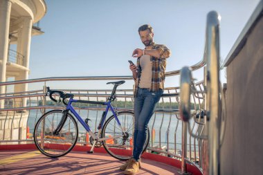 Endişeli adam caddede akıllı saate bakıyor.