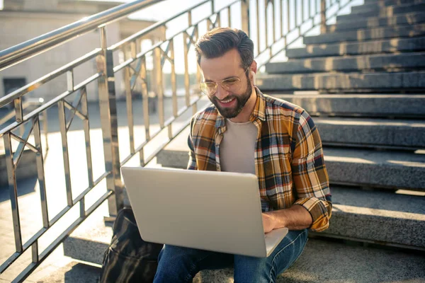 Lachender Mann schaut auf Laptop auf Stadttreppe — Stockfoto