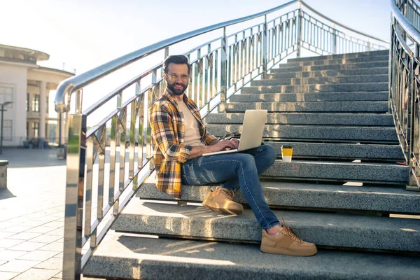 Uomo attraente seduto con computer portatile sulle scale — Foto Stock