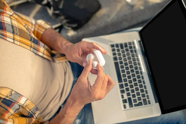 Wireless white headphones with case in mens hands