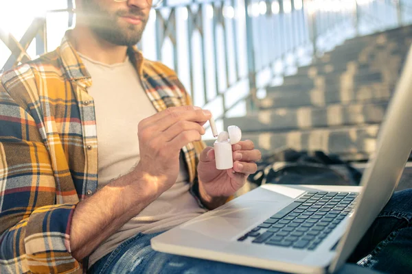 Uomo con laptop su scale con cuffie wireless — Foto Stock