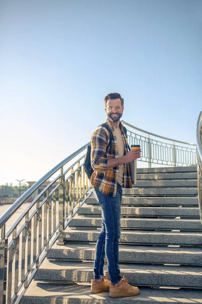 Homme souriant avec café debout se retournant sur les marches — Photo