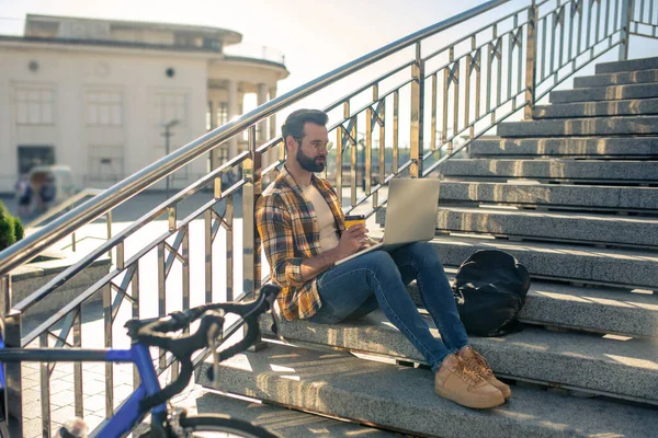 Man traveling on bicycle resting on the stairs