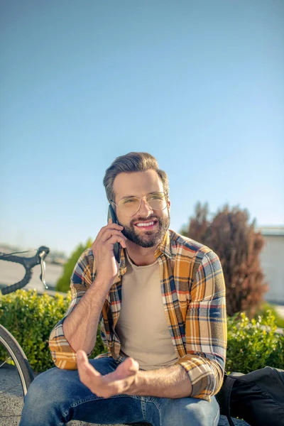 Succesvolle man aan het praten op smartphone zittend op straat — Stockfoto