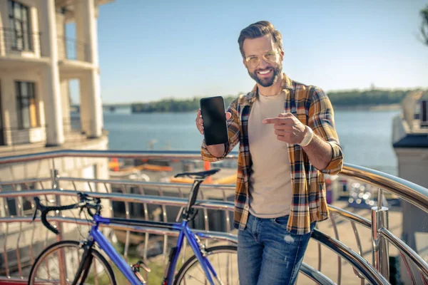 Man showing smartphone screen while standing in outdoors — Stock Photo, Image