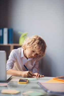 Tatlı sarışın çocuk bir şeyler yazıyor ve meşgul görünüyor.