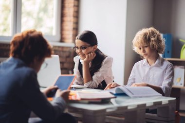 Sınıfta oturan ve ders çalışan üç sınıf arkadaşı.