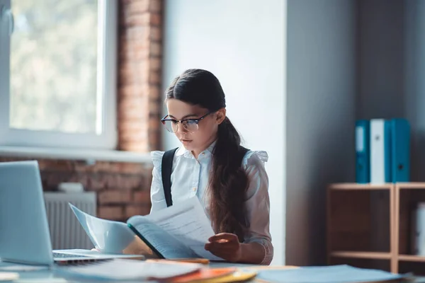 Brunette meisje in bril het lezen van een rapport en kijken verstoord — Stockfoto