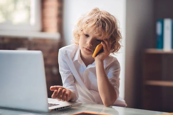 Leuke blonde jongen zitten en praten op de telefoon — Stockfoto