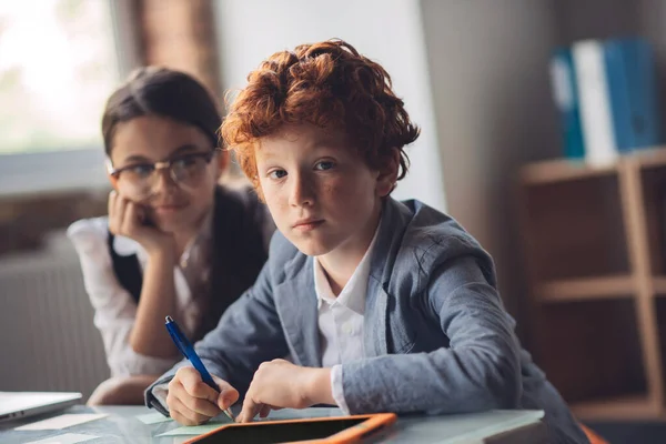 Niño pelirrojo estudiando con su amigo y luciendo reflexivo —  Fotos de Stock