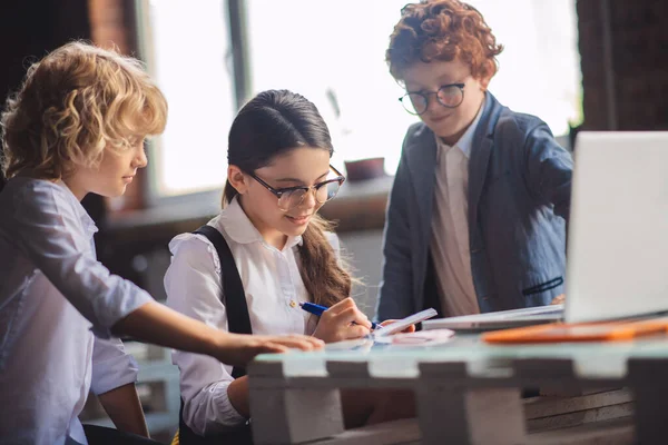 Three cute kids working on lessons together and looking involved — Stock Photo, Image