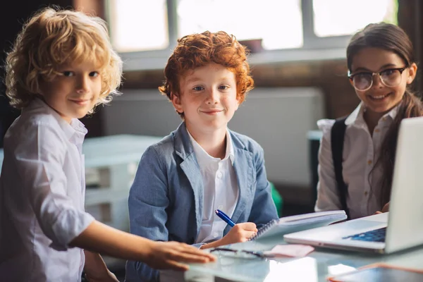 Három aranyos gyerek tanul az osztályteremben és boldognak tűnnek. — Stock Fotó