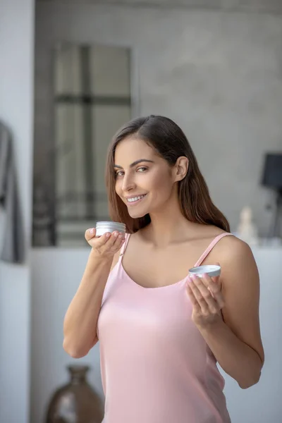 Schöne Frau, die eine Hautcreme riecht und zufrieden aussieht — Stockfoto