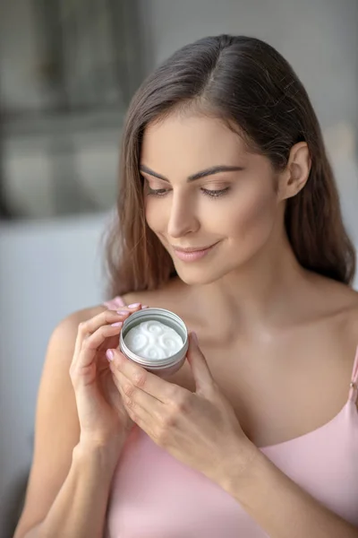 Hermosa mujer oliendo una crema para la piel y sintiéndose bien — Foto de Stock