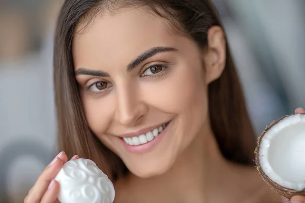 Hermosa mujer sosteniendo una barra de jabón de coco y sonriendo — Foto de Stock