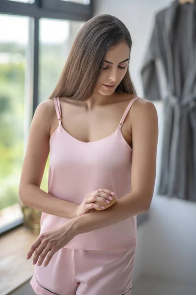 Mujer bonita frotándose el brazo con una esponja — Foto de Stock