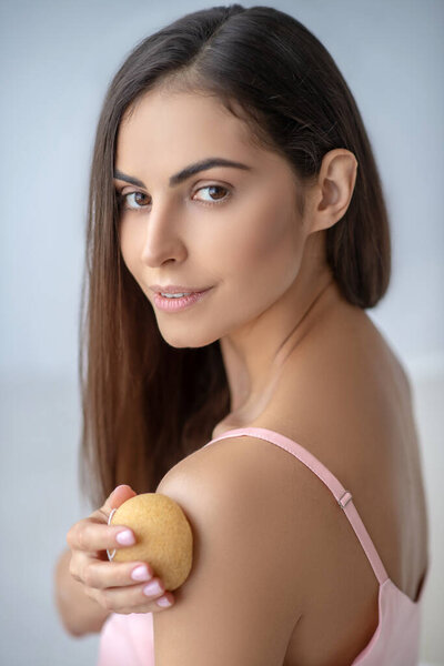 Dark-haired woman rubbing her arm with a sponge