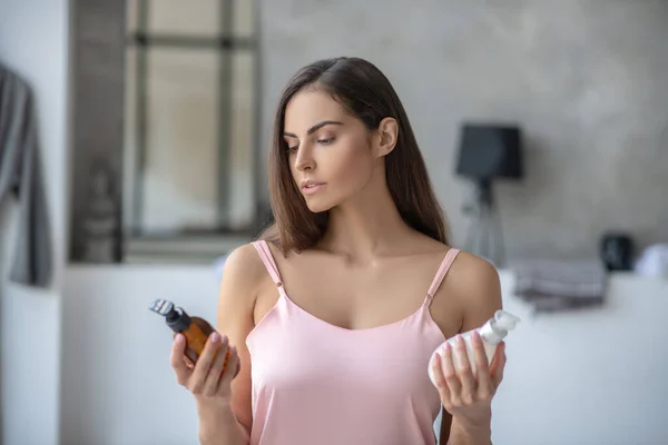 Mujer guapa de pelo oscuro eligiendo una loción corporal — Foto de Stock