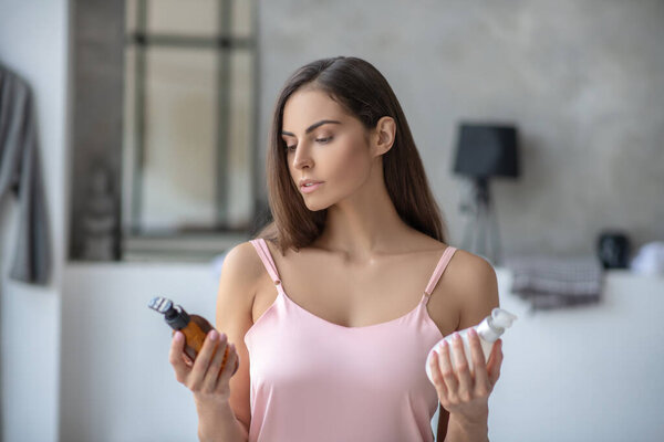 Dark-haired pretty woman choosing a body lotion