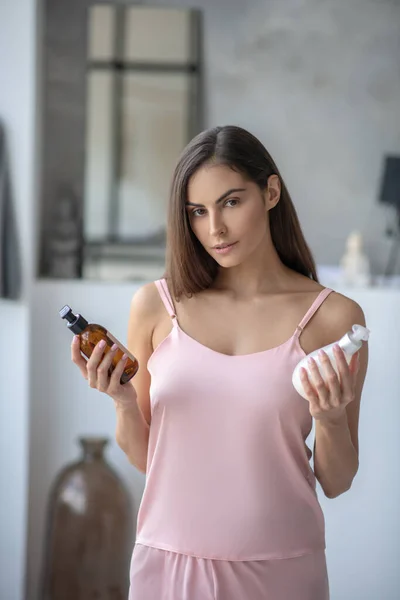 Mörkhårig vacker kvinna som håller två flaskor body lotion — Stockfoto