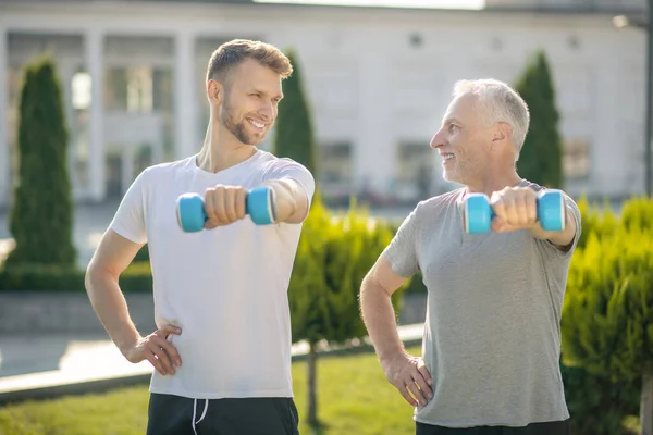 Jonge man met baard en volwassen man met halters, naar elkaar kijkend — Stockfoto