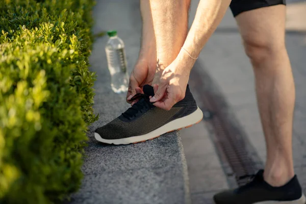 Siyah spor ayakkabılarını bağlayan erkek ellerinin yakın çekimi. — Stok fotoğraf