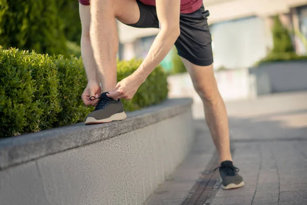 Großaufnahme männlicher Hände, die schwarze Turnschuhe schnüren — Stockfoto